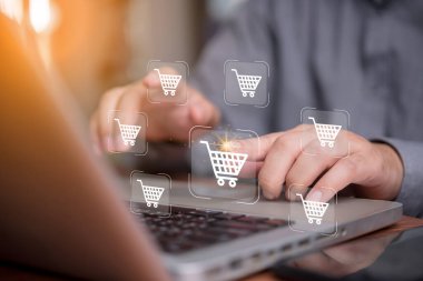 İnternetten alışveriş konsepti. Sanal araba simgelerine sahip dizüstü bilgisayar kullanan, e-ticaret, dijital işlemler ve internet perakende satış ve çevrimiçi perakende satış yapan bir adam.