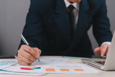 Finansal veri tablosunu inceleyen iş analisti ve piyasa performans değerlendirmesi toplantısı grafikleri. Mali rapor analizi, pasta grafikleri ve büyüme göstergeleriyle detaylı istatistikler gösteriyor