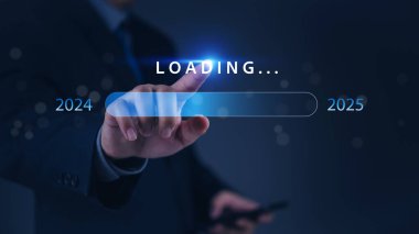 2024 'ten 2025' e geçişi olan bir yükleme barına işaret eden bir el, ilerlemeyi ve geleceği simgeliyor..