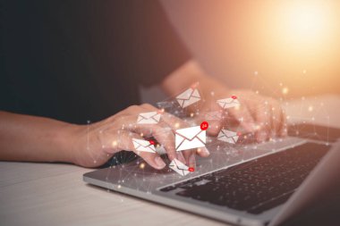 Dijital e- posta simgeleri yüzen, çevrimiçi pazarlama iletişimi ve gerçek zamanlı bildirimleri olan bir dizüstü bilgisayarda yazı yazan eller.