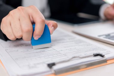 Ofisteki resmi bir belgeye pul yapıştıran bir şirket çalışanı, belge onayı ve evrak işleme sürecini gözler önüne seriyor..