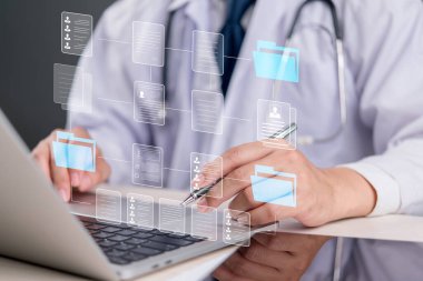 Tıbbi bir uzman, hasta verilerini ve tıbbi belgeleri dijital arayüzle analiz ediyor. Sahne, sağlık hizmetlerinde elektronik sağlık kayıtlarının (AİHM) kullanımını vurguluyor.