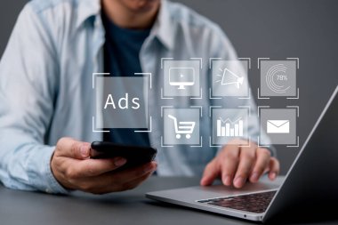 Bilgisayarı ve akıllı telefonu kullanan adamla dijital pazarlama kavramı, çevrimiçi reklamcılık, sosyal medya kampanyası, analitik, e-ticaret araçları ve müşteri hedefleme stratejisi.