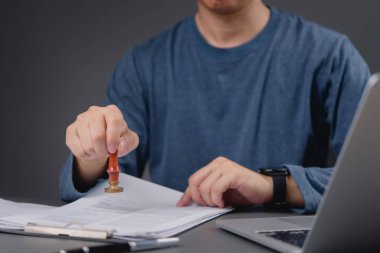 Profesyonel ofis çalışanı evrak üzerinde damga kullanıyor, idari süreci ve belgelerin resmi onayını gösteriyor.