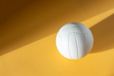 White volleyball leather ball on yellow background. Top view. Game equipment horizontal sport theme poster, greeting cards, headers, website and app