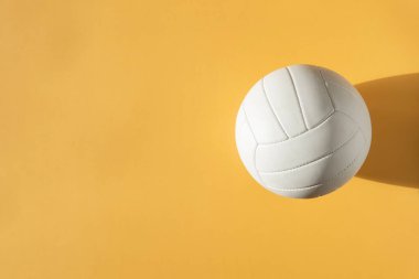 White volleyball leather ball on yellow background. Top view. Game equipment horizontal sport theme poster, greeting cards, headers, website and app
