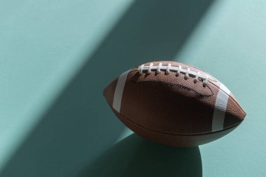 American football leather ball on mint color background. Top view. Game equipment horizontal sport theme poster, greeting cards, headers, website and app