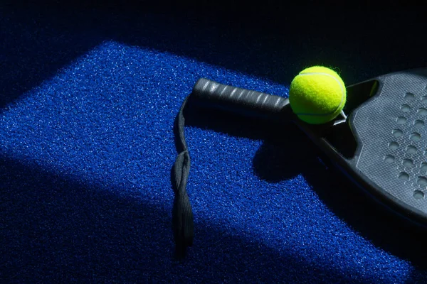 青の背景に自然光と黒のプロパドルテニスラケットとボール 水平スポーツのテーマのポスター グリーティングカード ヘッダー ウェブサイトとアプリ — ストック写真