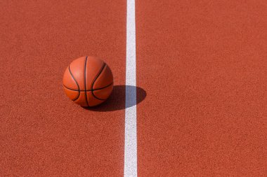 Turuncu spor salonunun sahasında beyaz çizgili yeni turuncu basketbol topu. Yatay spor temalı poster, tebrik kartları, başlıklar, web sitesi ve uygulama