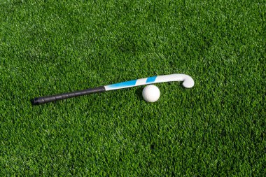 Çim hokeyi sopası ve top yeşil çimlerde. Takım sporu konsepti. Yatay spor temalı poster, tebrik kartları, başlıklar, web sitesi ve uygulama