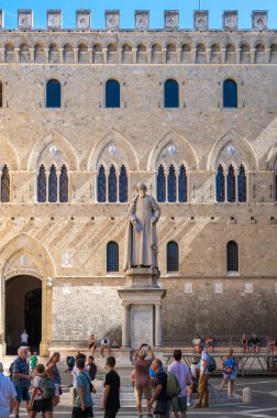 A medieval square of Piazza Salimbeni with a statue of Sallustio Bandini in Siena, Italy clipart