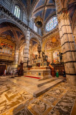 Siena, İtalya - 9 Ağustos 2023: Siena Katedrali 'nin nefes kesici iç manzarası, çizgili kolonları, yüksek tavanları ve karmaşık mermer döşeme tasarımları sergilenmektedir..