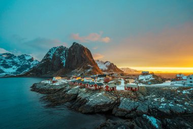 Lofoten Adası 'ndaki Hamnoy' un manzarası. Gün batımında arka planda karla kaplı dağlar..