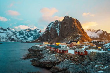 Lofoten Adası 'ndaki Hamnoy' un manzarası. Gün batımında arka planda karla kaplı dağlar..