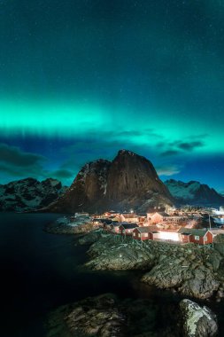 Kuzey ışıkları Hamnoy 'un üzerinde Lofoten Adası' nda dağlar ve denizlerle.