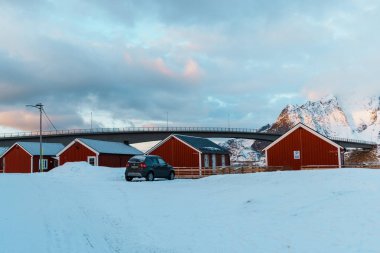 Lofoten Adası 'ndaki Hamnoy' un manzarası. Gün batımında arka planda karla kaplı dağlar..