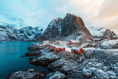 Lofoten Adası 'ndaki Hamnoy' un manzarası. Gün batımında arka planda karla kaplı dağlar..