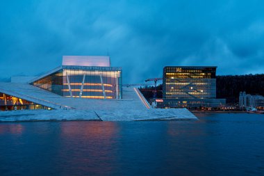 Oslo, Norveç - 13 Nisan 2024: Oslo Opera Evi 'nin çevresindeki insanların yürüyüp dinlendiği bir manzarası. Sahne alacakaranlıkta çekilmiştir..