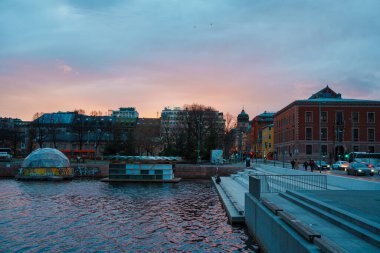 Oslo, Norveç - 13 Nisan 2024: Oslo limanının çevresi insanların yürüdüğü ve dinlendiği bir manzarası. Sahne alacakaranlıkta çekilmiştir..