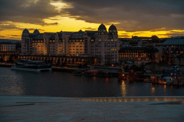 Oslo, Norveç - 13 Nisan 2024: Oslo Opera Evi 'nin çevresindeki insanların yürüyüp dinlendiği bir manzarası. Sahne alacakaranlıkta çekilmiştir..