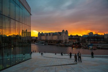 Oslo, Norveç - 13 Nisan 2024: Oslo Opera Evi 'nin çevresindeki insanların yürüyüp dinlendiği bir manzarası. Sahne alacakaranlıkta çekilmiştir..
