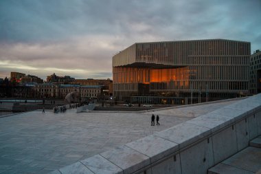 Oslo, Norveç - 13 Nisan 2024: Oslo Opera Evi 'nin çevresindeki insanların yürüyüp dinlendiği bir manzarası. Sahne alacakaranlıkta çekilmiştir..
