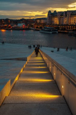 Oslo, Norveç - 13 Nisan 2024: Oslo Opera Evi 'nin çevresindeki insanların yürüyüp dinlendiği bir manzarası. Sahne alacakaranlıkta çekilmiştir..