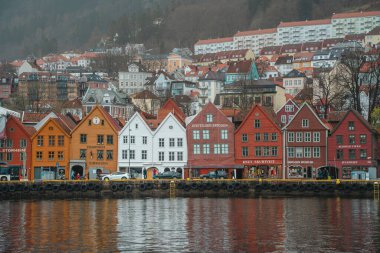 Norveç 'in Bergen kentindeki Iconic Bryggen Rıhtımı' nda bulutlu bir günde liman boyunca renkli cepheli geleneksel ahşap binalar bulunuyor..