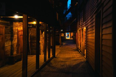 Norveç, Bergen 'deki Bryggen İskelesi' nden atmosferik gece sahneleri, rahat dükkanları, aydınlık sokakları ve sıcak ışıklandırmadaki ahşap tarihi binaları gösteriyor..