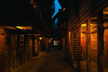 Norveç, Bergen 'deki Bryggen İskelesi' nden atmosferik gece sahneleri, rahat dükkanları, aydınlık sokakları ve sıcak ışıklandırmadaki ahşap tarihi binaları gösteriyor..