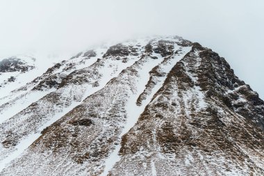 Kışın şafak vakti Lofoten 'daki bir dağ sırasının dramatik karlı manzarası. Norveç.