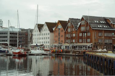 Tromso, Norveç - 10 Nisan 2024: Tromso, Norveç 'ten büyüleyici kış manzaraları, renkli liman binaları, botlar, karla kaplı dağlar ve manzaralı Arktik kıyısı manzaraları.