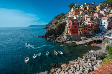 Riomaggiore, İtalya - 7 Şubat 2022: Renkli binalar, kayalık kayalıklar, turkuaz deniz, tekneler ve turistlerle Riomaggiore, Cinque Terre 'nin resimli sahnesi.