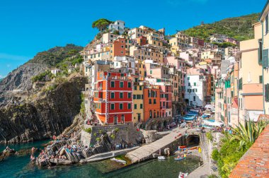 Riomaggiore, İtalya - 7 Şubat 2022: Renkli binalar, kayalık kayalıklar, turkuaz deniz, tekneler ve turistlerle Riomaggiore, Cinque Terre 'nin resimli sahnesi.