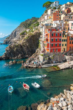 Riomaggiore, İtalya - 7 Şubat 2022: Renkli binalar, kayalık kayalıklar, turkuaz deniz, tekneler ve turistlerle Riomaggiore, Cinque Terre 'nin resimli sahnesi.