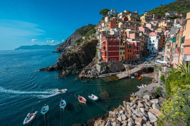 Riomaggiore, İtalya - 7 Şubat 2022: Renkli binalar, kayalık kayalıklar, turkuaz deniz, tekneler ve turistlerle Riomaggiore, Cinque Terre 'nin resimli sahnesi.