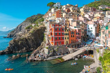 Riomaggiore, İtalya - 7 Şubat 2022: Renkli binalar, kayalık kayalıklar, turkuaz deniz, tekneler ve turistlerle Riomaggiore, Cinque Terre 'nin resimli sahnesi.
