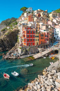 Riomaggiore, İtalya - 7 Şubat 2022: Renkli binalar, kayalık kayalıklar, turkuaz deniz, tekneler ve turistlerle Riomaggiore, Cinque Terre 'nin resimli sahnesi.