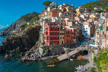Riomaggiore, İtalya - 7 Şubat 2022: Renkli binalar, kayalık kayalıklar, turkuaz deniz, tekneler ve turistlerle Riomaggiore, Cinque Terre 'nin resimli sahnesi.