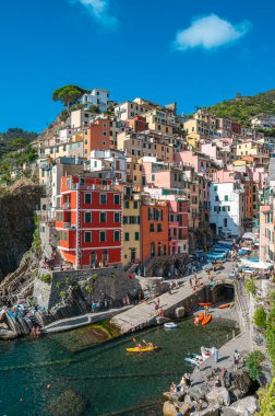 Riomaggiore, İtalya - 7 Şubat 2022: Renkli binalar, kayalık kayalıklar, turkuaz deniz, tekneler ve turistlerle Riomaggiore, Cinque Terre 'nin resimli sahnesi.