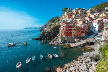 Riomaggiore, İtalya - 7 Şubat 2022: Renkli binalar, kayalık kayalıklar, turkuaz deniz, tekneler ve turistlerle Riomaggiore, Cinque Terre 'nin resimli sahnesi.