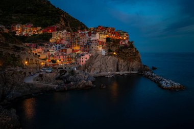 Manarola 'nın çarpıcı panoramik manzarası İtalyan Rivierası boyunca canlı bir gecede Ligurian Denizi' nin üzerindeki uçurumlara tünemişti..