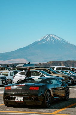 Hakone, Japonya - 10 Aralık 2023: Japonya 'nın Owakudani kentindeki manzaralı otopark, araç ve turistlerle dolu, arka planda kar kaplı Fuji Dağı net bir görünüm sağlıyor.
