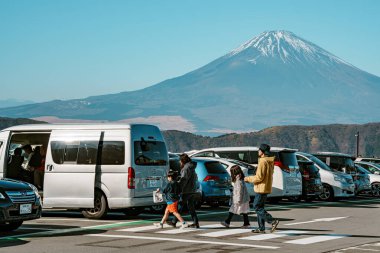 Hakone, Japonya - 10 Aralık 2023: Japonya 'nın Owakudani kentindeki manzaralı otopark, araç ve turistlerle dolu, arka planda kar kaplı Fuji Dağı net bir görünüm sağlıyor.