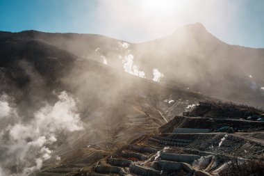 Hakone, Japonya 'da Owakudani' nin dramatik jeotermal manzarası, yükselen buhar bacaları, engebeli arazi ve manzaralı bir halat gezisi.