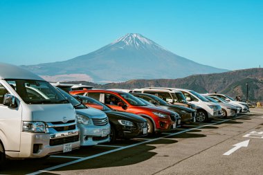 Hakone, Japonya - 10 Aralık 2023: Japonya 'nın Owakudani kentindeki manzaralı otopark, araç ve turistlerle dolu, arka planda kar kaplı Fuji Dağı net bir görünüm sağlıyor.