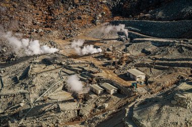 Hakone, Japonya 'da Owakudani' nin dramatik jeotermal manzarası, yükselen buhar bacaları, engebeli arazi ve manzaralı bir halat gezisi.