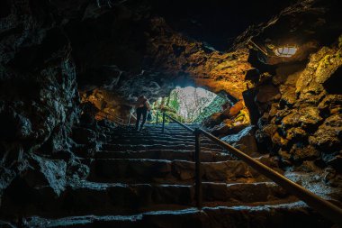 Yürüyüşçüler, Fugaku Rüzgar Mağarası 'nın karanlık ve gizemli girişine yaklaşan Aokigahara' nın yemyeşil ormanına doğru iniyor..