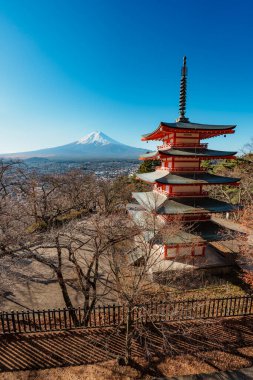 İkonik Chureito Pagoda ile Fuji Dağı ve Fujiyoshida şehri mavi gökyüzünün altında panoramik bir manzara.