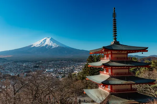İkonik Chureito Pagoda ile Fuji Dağı ve Fujiyoshida şehri mavi gökyüzünün altında panoramik bir manzara.